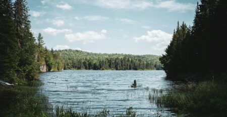 person sitting on rock in lake during daytime